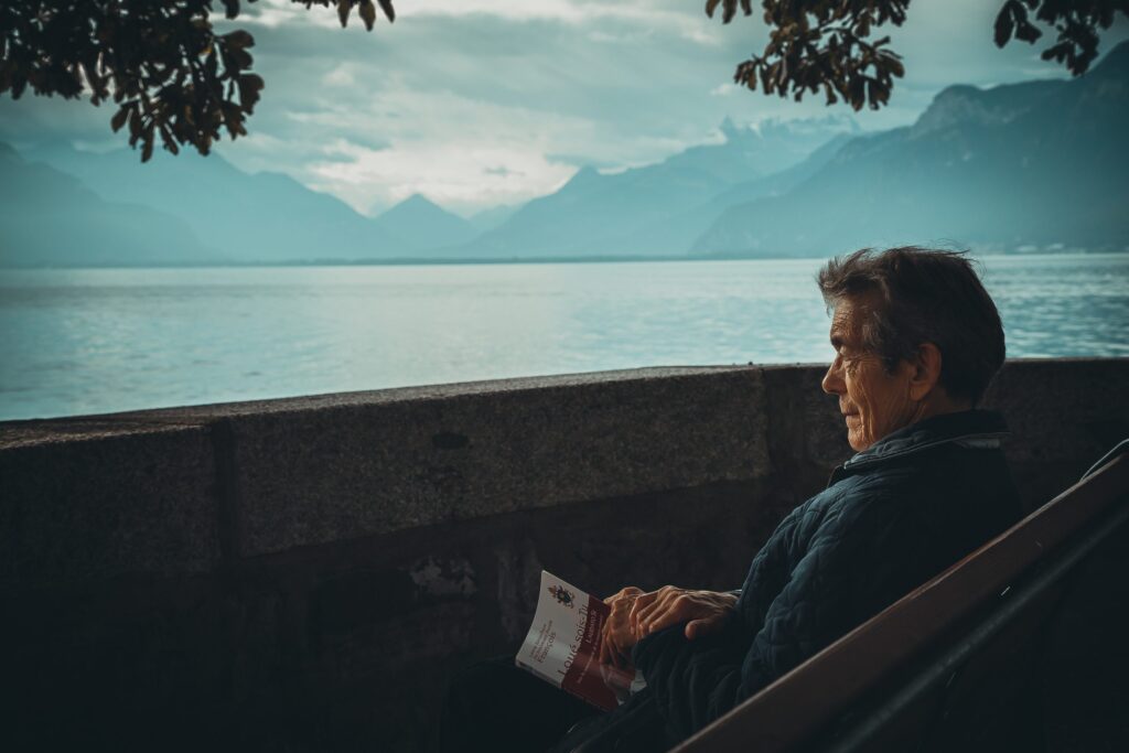 An old man focusing on a beautiful view of a lake which headlines our blog describing the focusing (mindfulness) skills of elderly Japanese people who practice Ikagai.